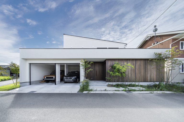 片流れ屋根が印象的な白い外観に、ガレージと木のアクセントを組み合わせた住まい